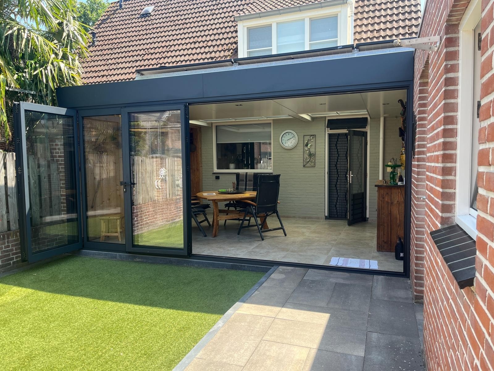 Black aluminum bifold glass doors fully opened connecting indoor living space to outdoor patio area